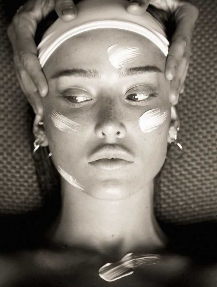 Black-and-white close-up of a woman receiving a facial with cream on her skin